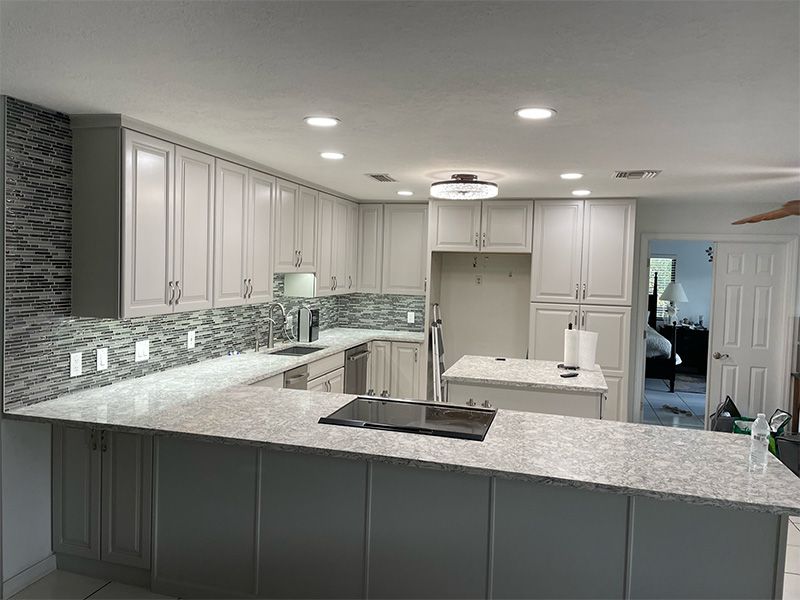 Newly remodeled kitchen with gray cabinets, granite counters, and tile backsplash.
