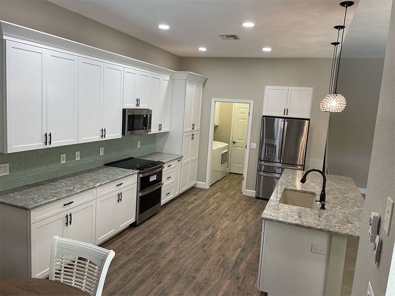 Modern kitchen with white cabinets, stainless steel appliances, and gray countertops.