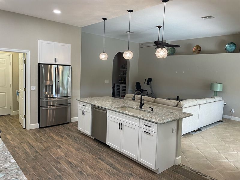 Modern kitchen with island, refrigerator, and seating area with a sofa.
