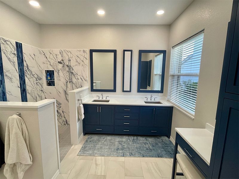 Spacious modern bathroom with navy blue vanity, marble shower, and white accents.