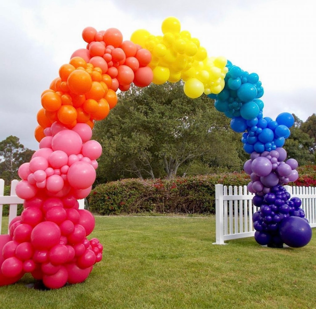 A bunch of colorful balloons in the shape of a rainbow
