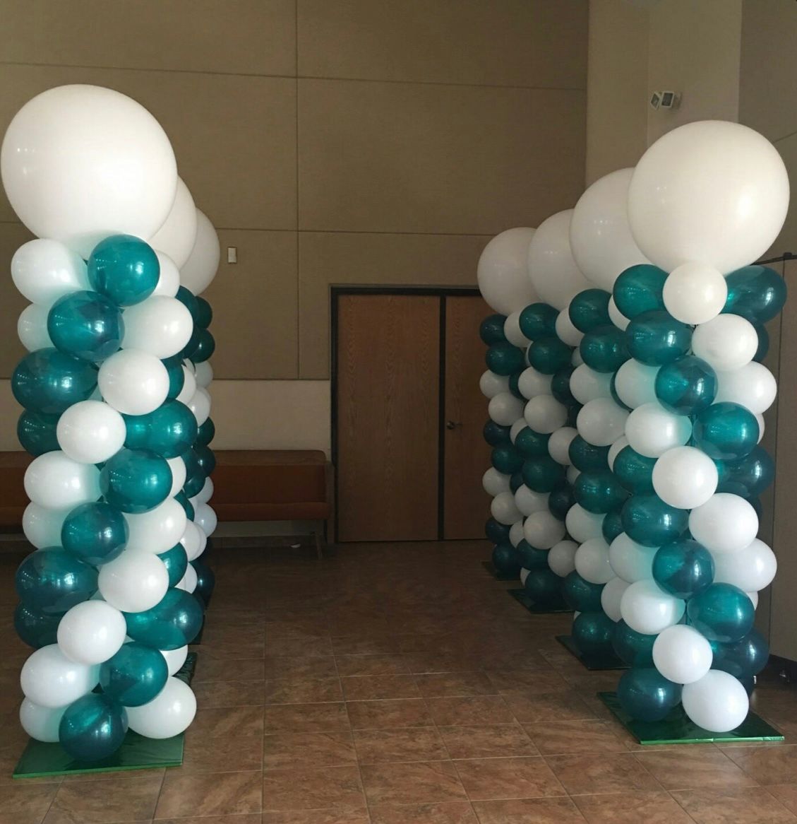 Two columns of green and white balloons in a room