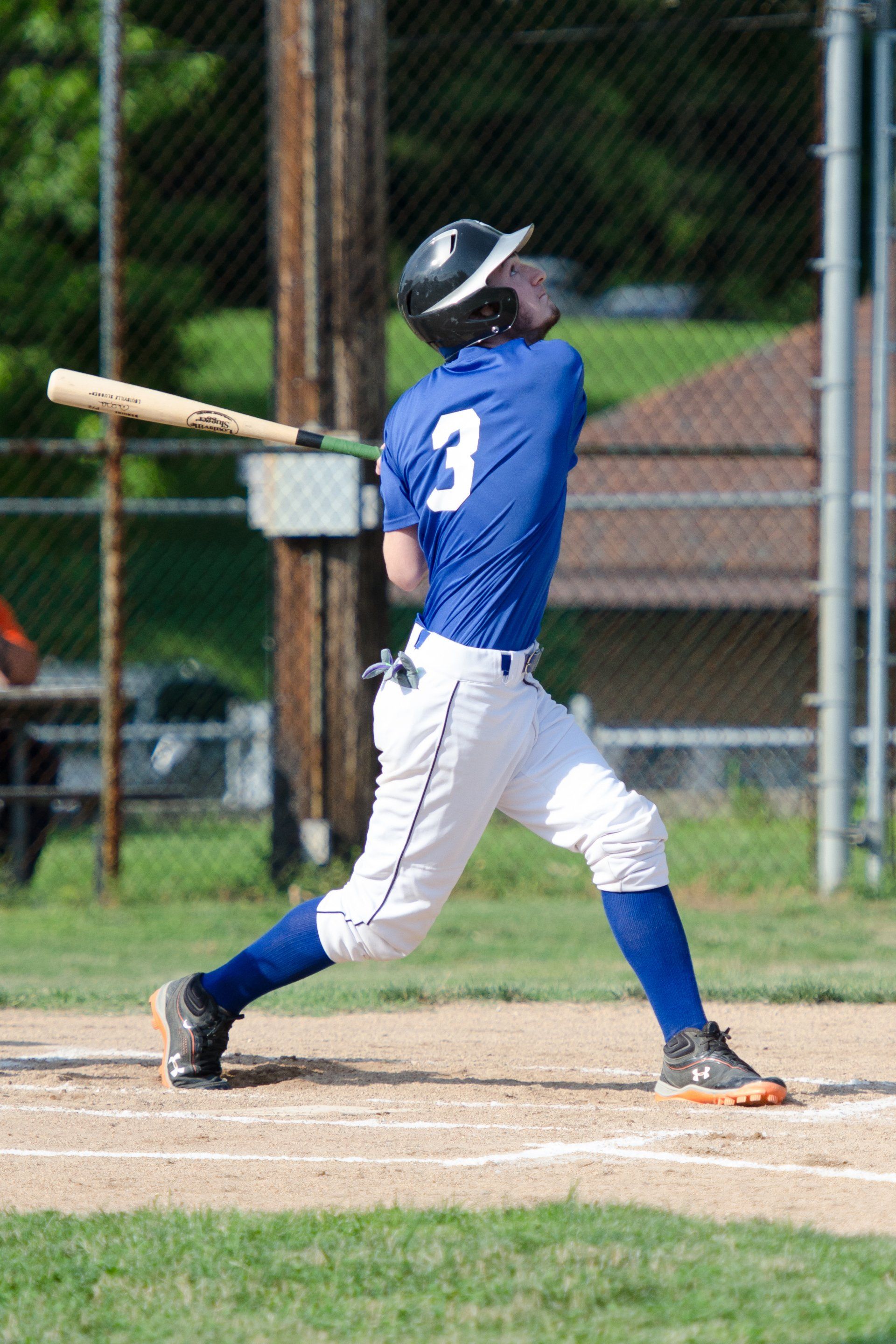 Baseball player in blue uniform hitting a ball, wearing a helmet and standing at home plate.