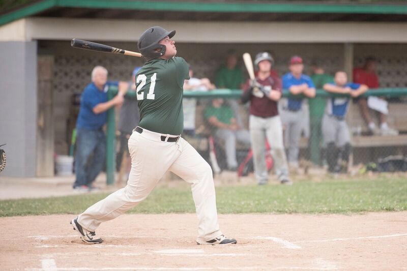 Baseball player in green jersey with number 21 swinging bat at game.