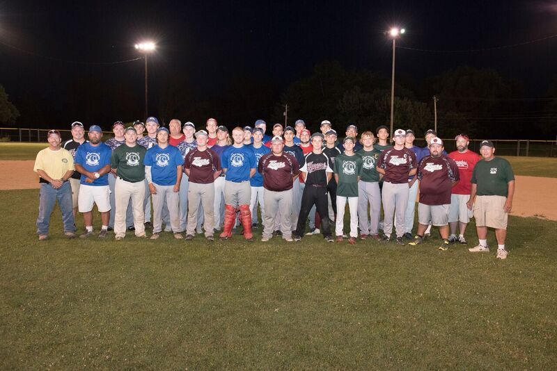 Group of baseball players in team uniforms standing on a field at night.