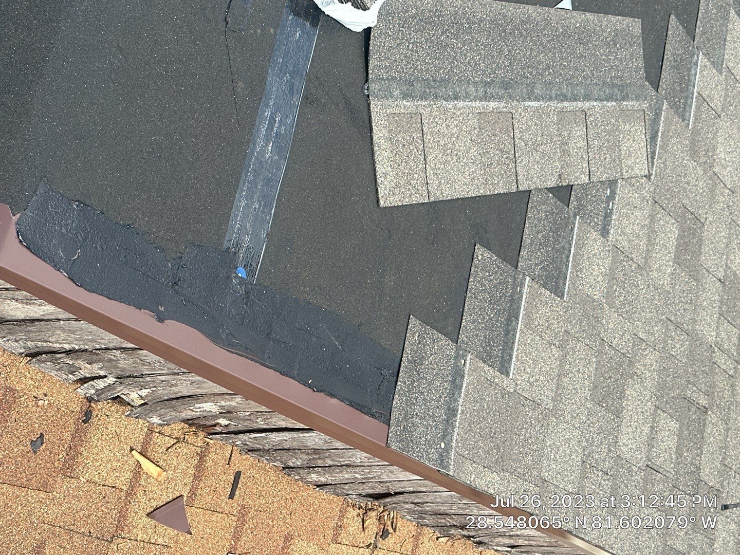 Roofing technician repairing damaged shingles on a residential roof.