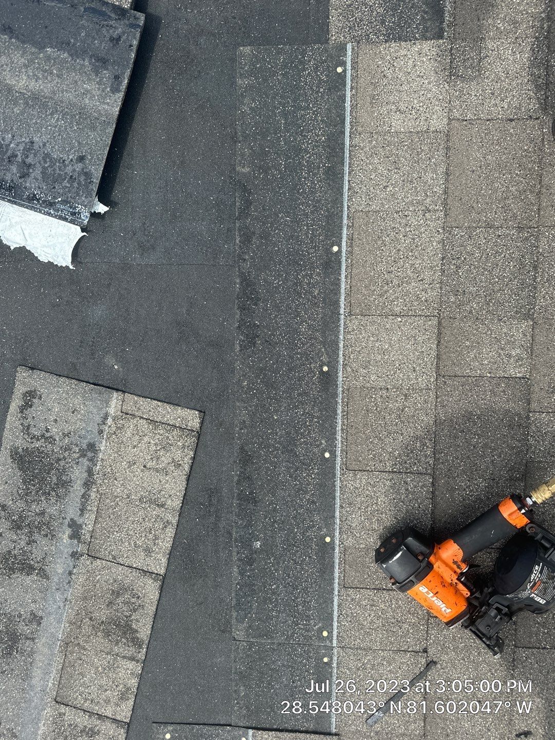 Roofing technician repairing damaged shingles on a residential roof.