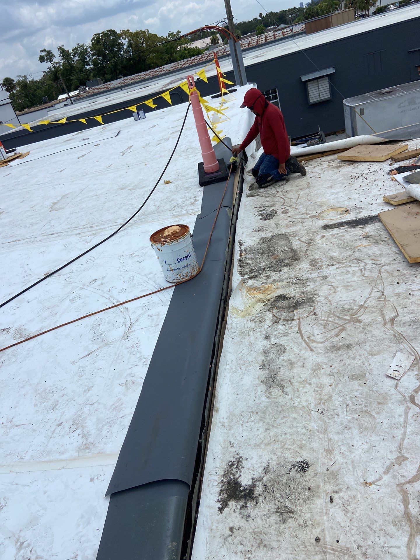 Technician applying single ply roofing material on a flat roof. Commercial roofing project in progress 
