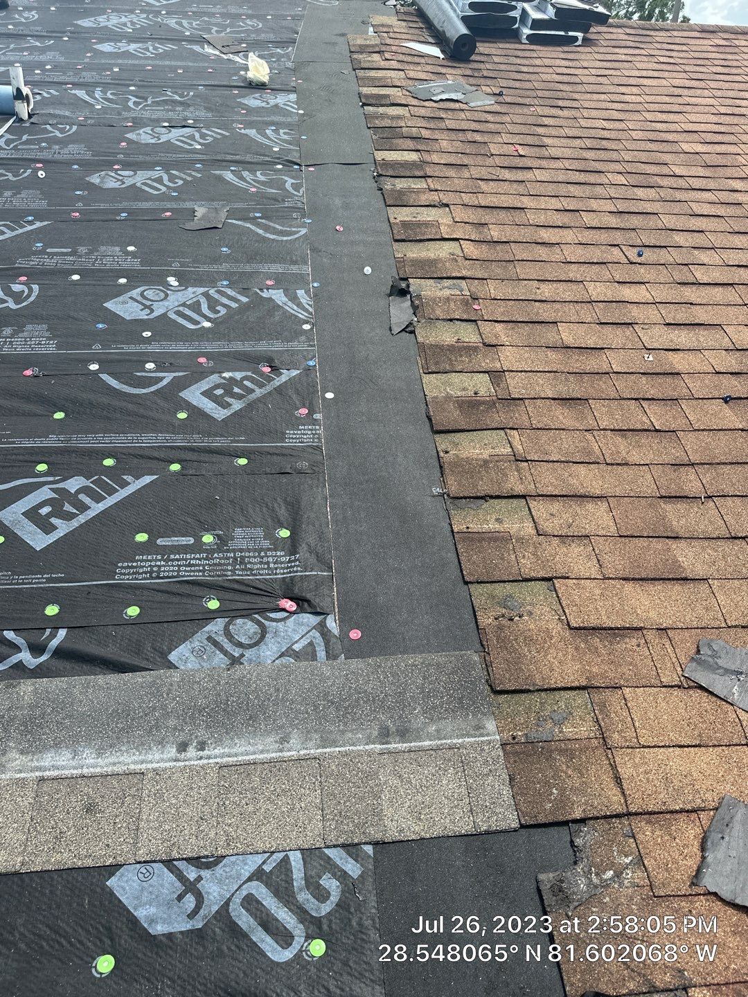 Roofing technician repairing damaged shingles on a residential roof.