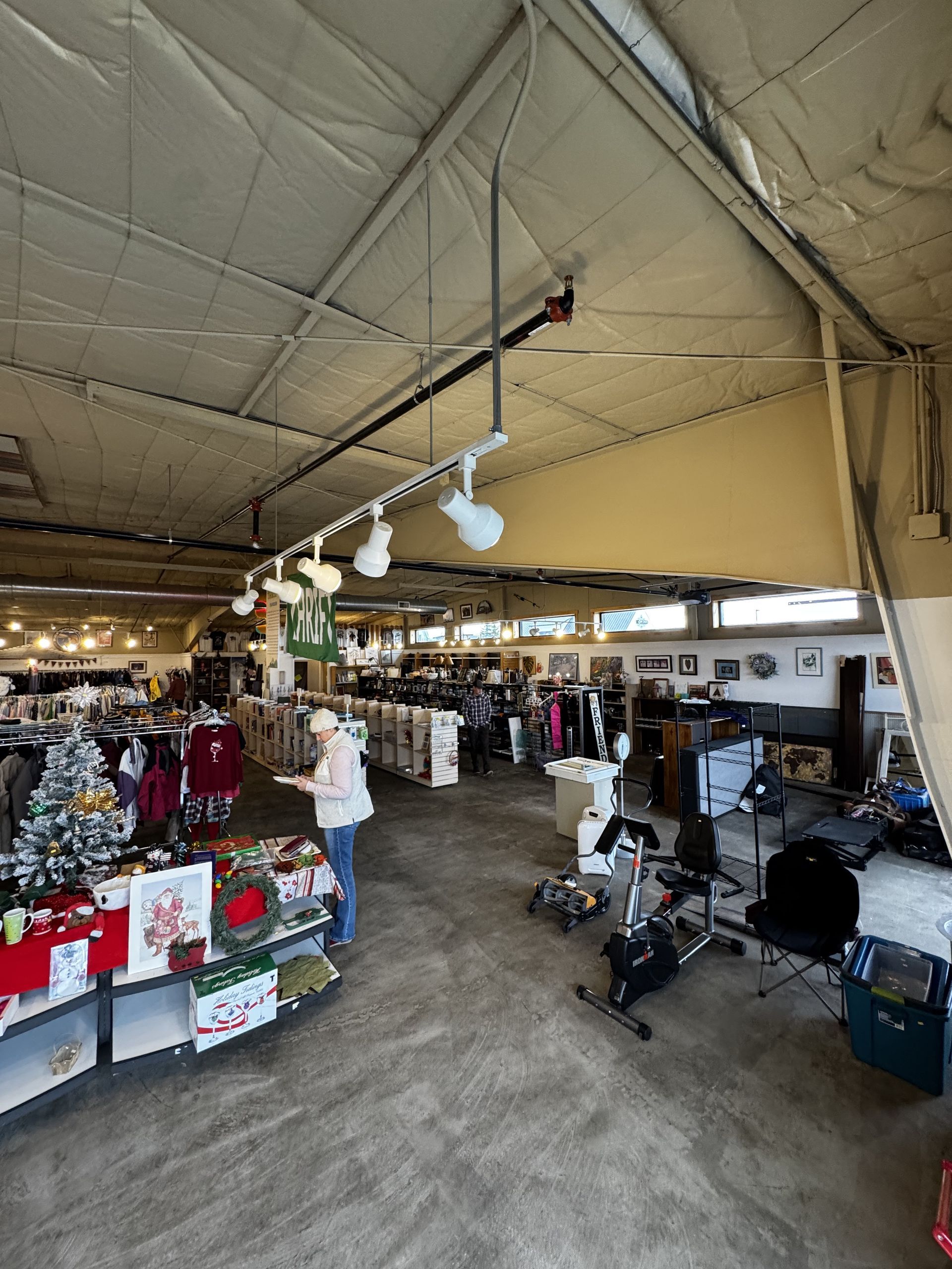 Inside a retail store, with shoppers and merchandise displayed. Overhead lighting is mounted.