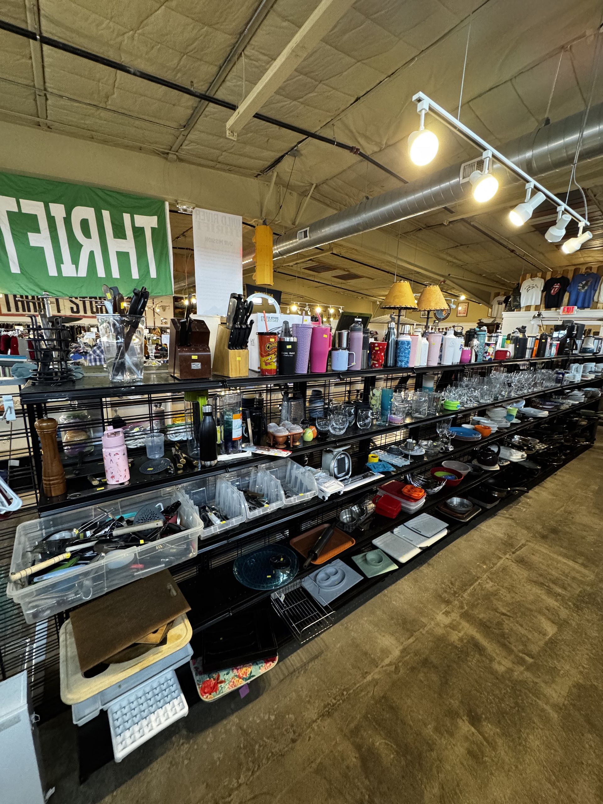 Thrift store aisle with shelves of items. Green