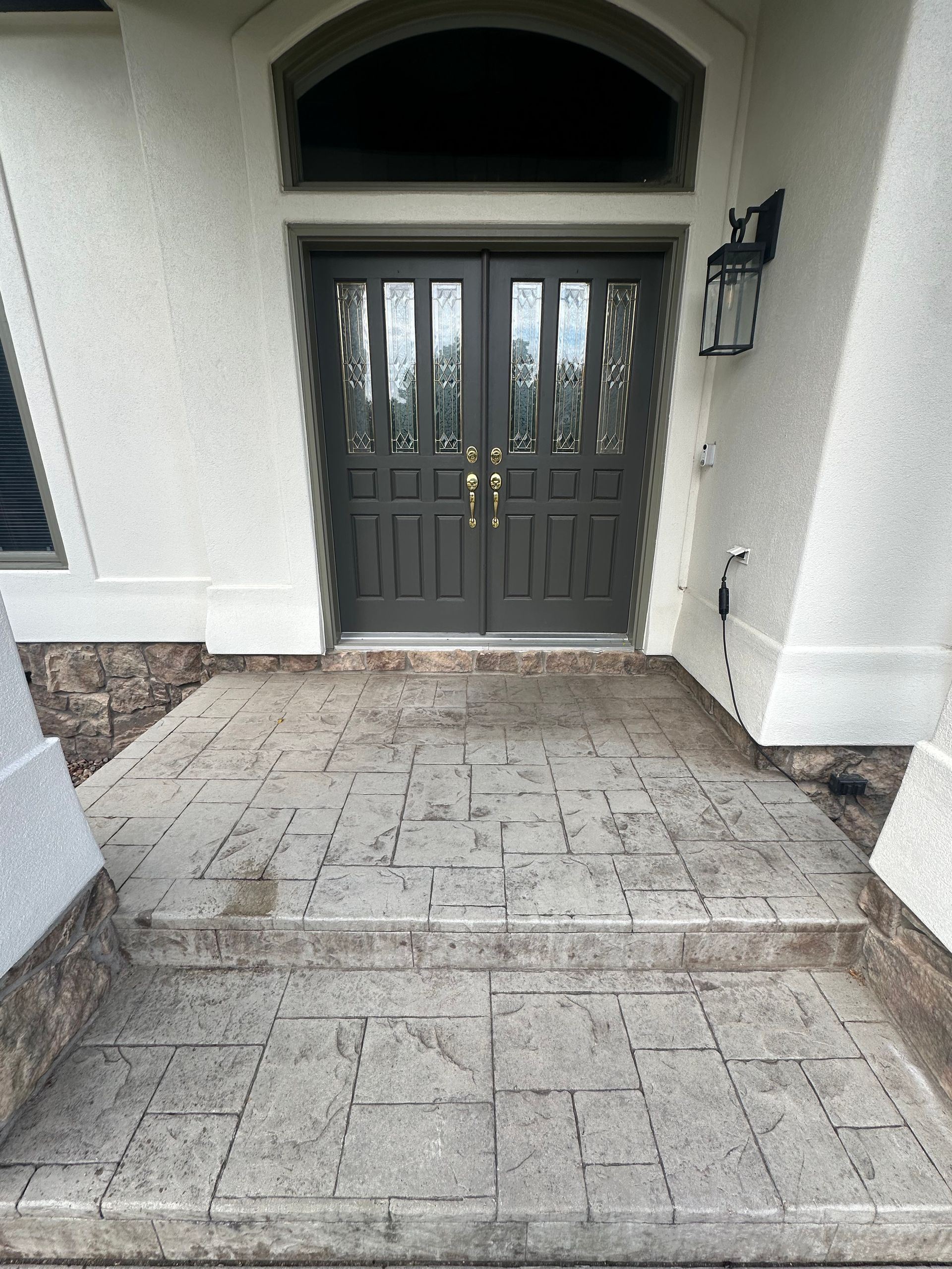 Gray double doors lead to a home with stone steps.