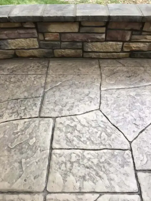 A close up of a concrete floor with a stone wall in the background.
