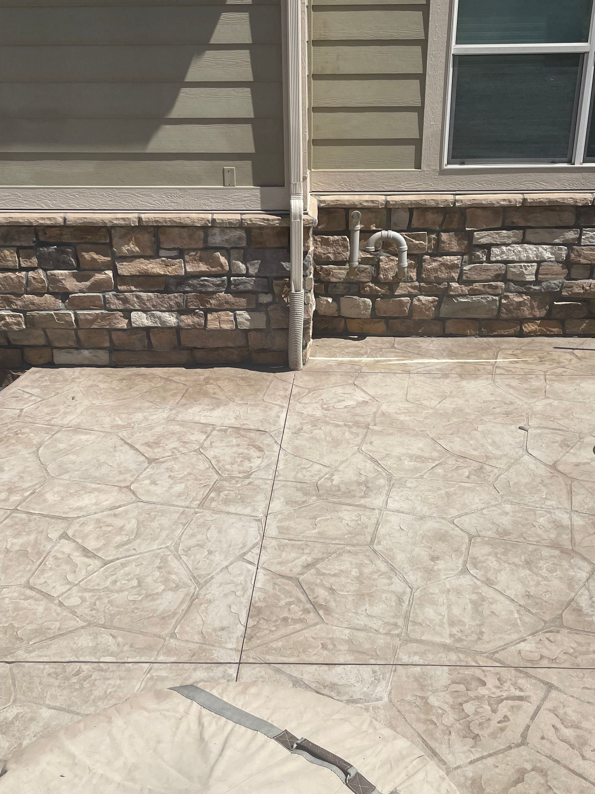 A concrete patio with a stone wall in the background