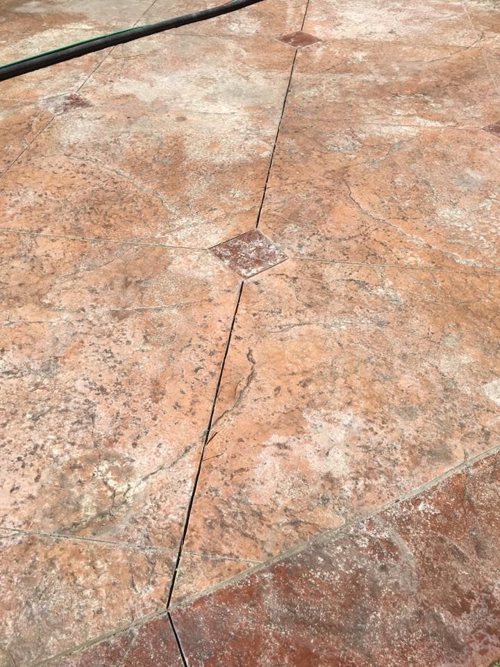 A close up of a concrete floor with a hose in the background.