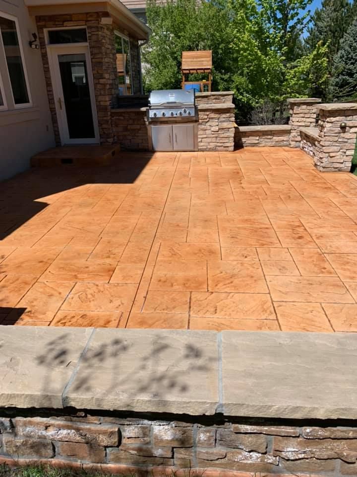 A patio with a grill and a brick wall in front of a house.