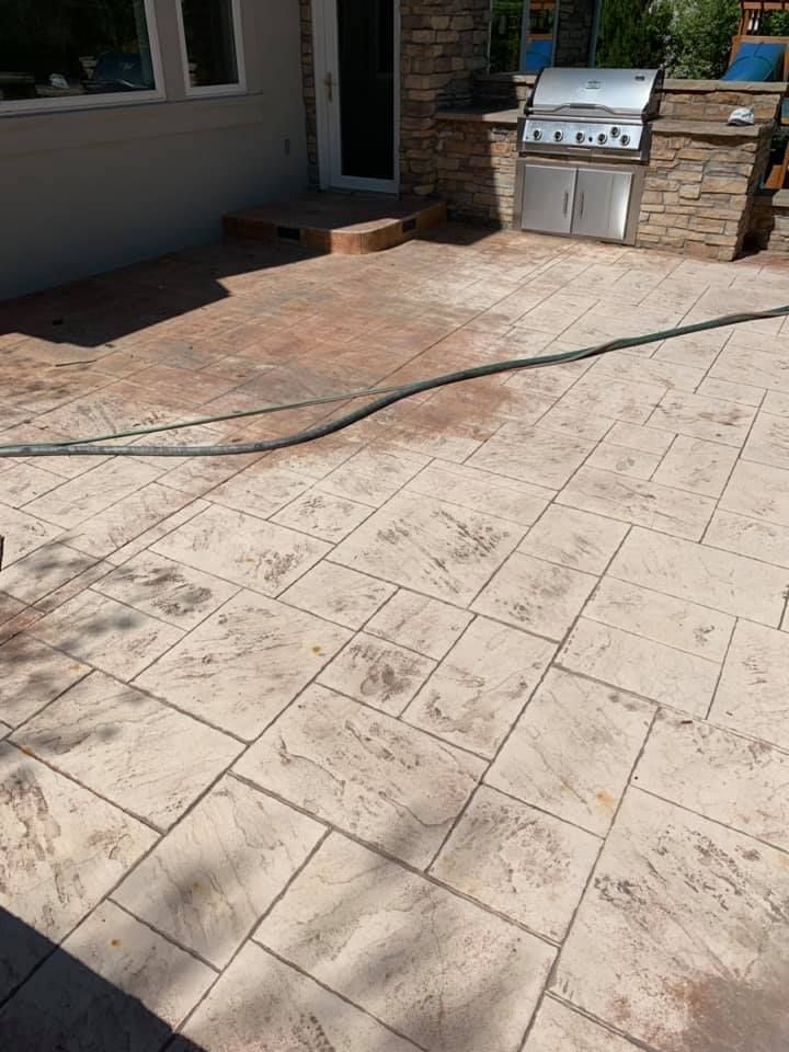 A patio with a grill and a hose on it.