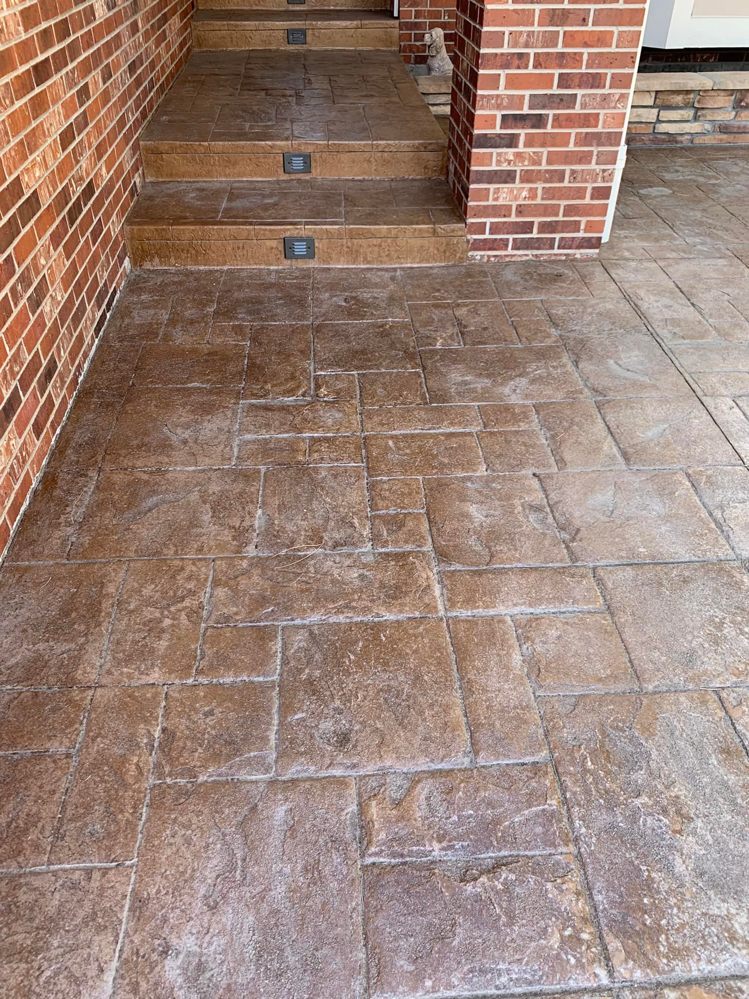 A concrete walkway with stairs leading up to a brick building.