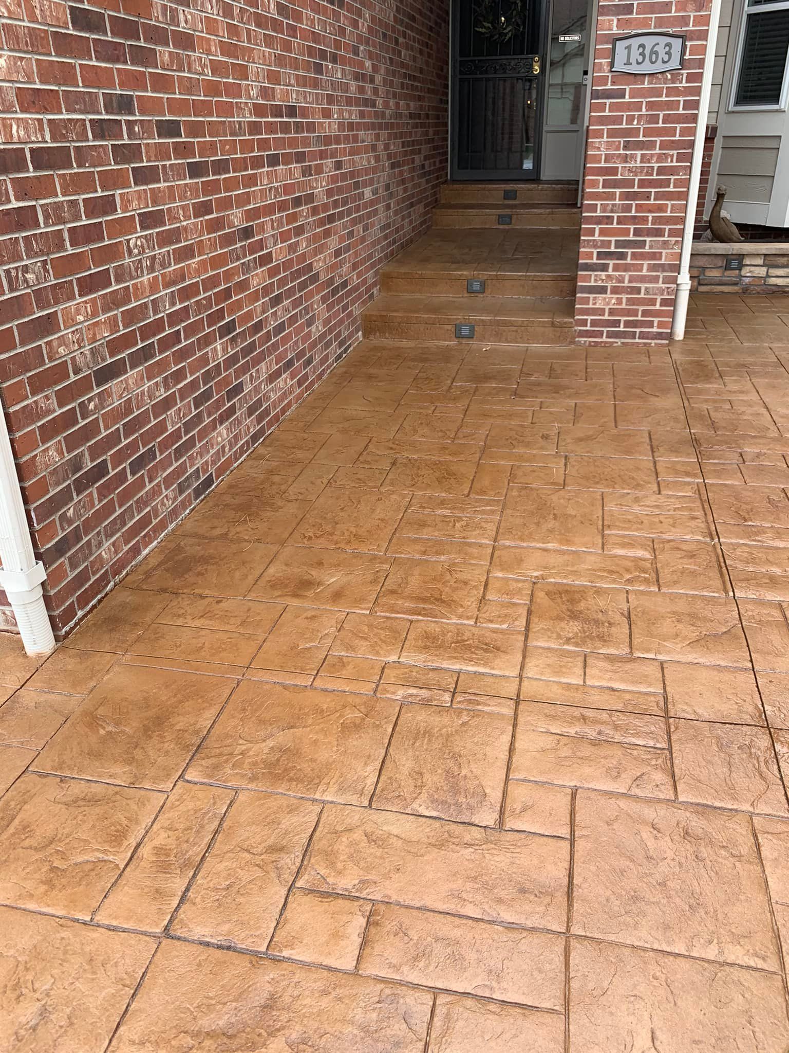 A brick building with a concrete walkway in front of it.