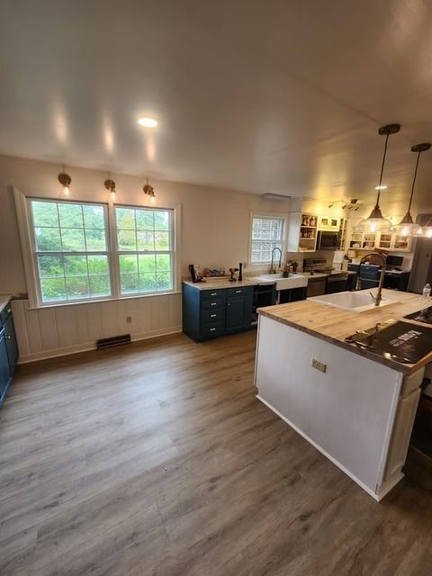 Spacious kitchen with wood-look flooring, white and navy cabinets, and a central island with a wooden countertop and sink.