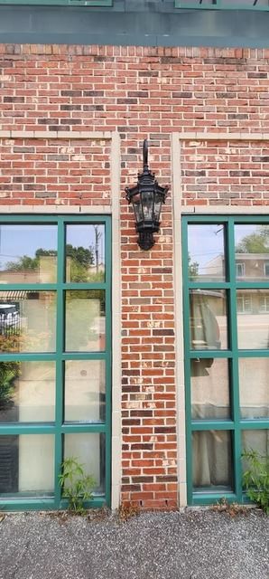 Brick building facade with green-framed windows, a black lantern, and a green trim at the top.