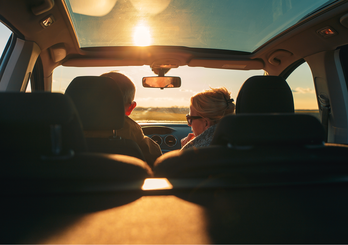 A group of people are sitting in a car looking out the window at the sun.