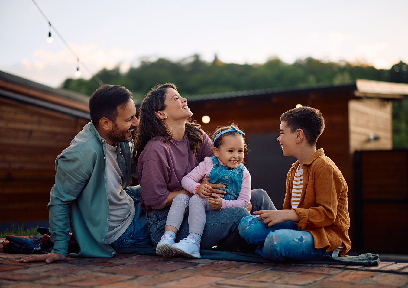 A family is sitting on the ground on a roof.