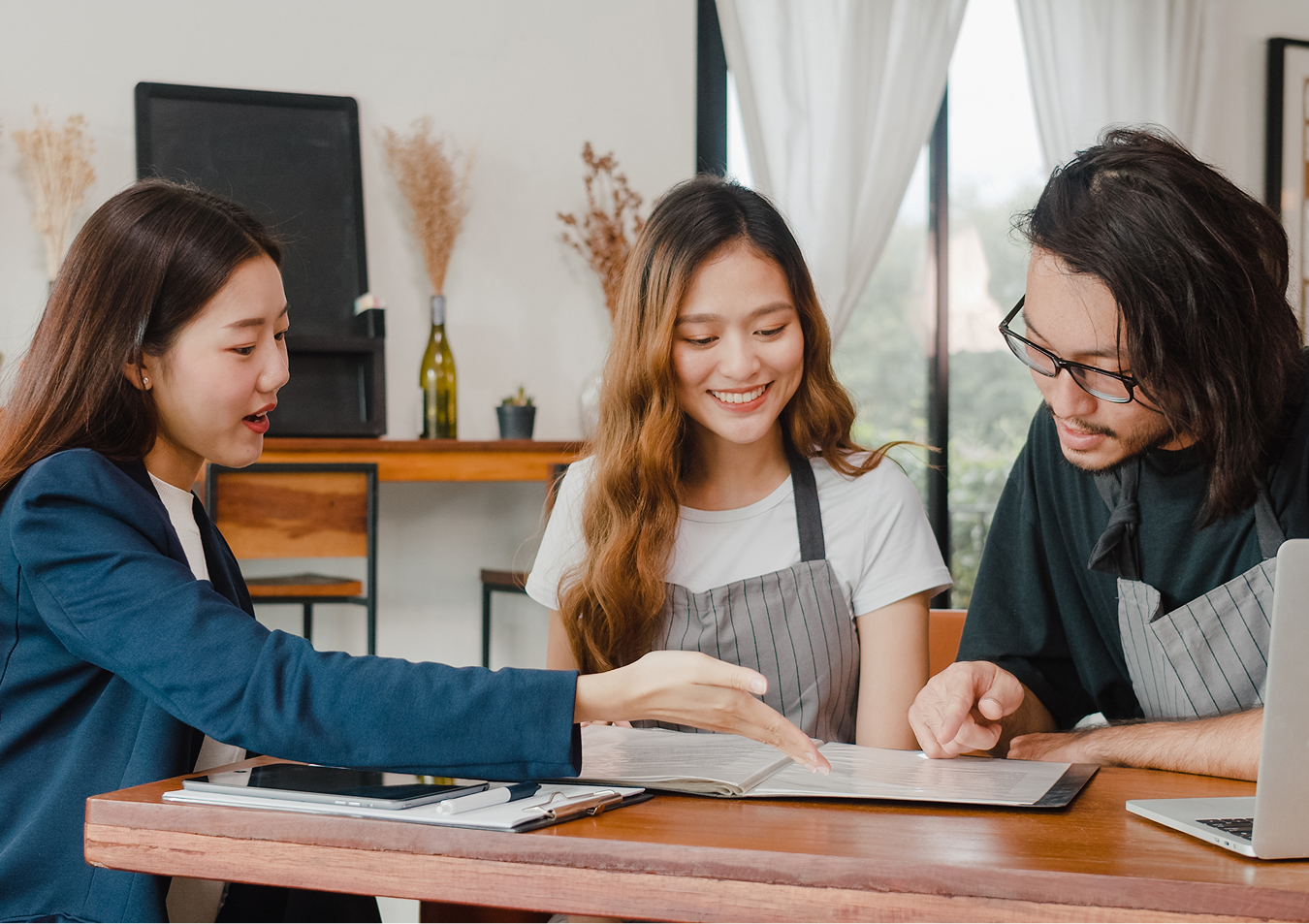A man and a woman are sitting at a table looking at a clipboard.
