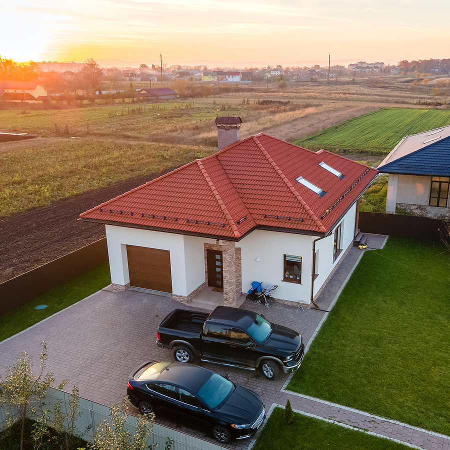 An aerial view of a house with two cars parked in front of it