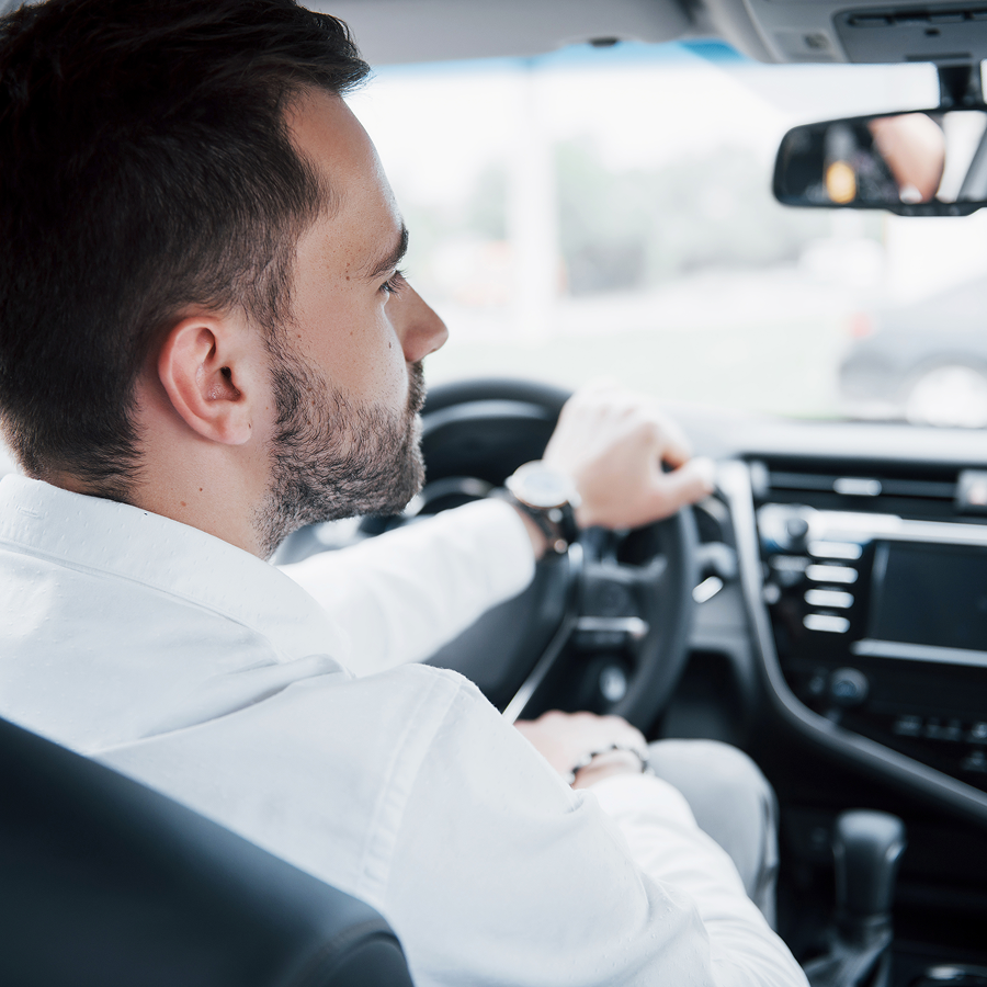 A man in a white shirt is driving a car