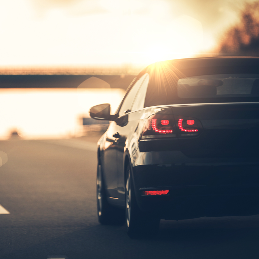 A car is parked on the side of the road near a body of water.