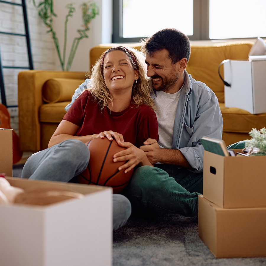 A man and a woman are sitting on the floor holding a basketball.