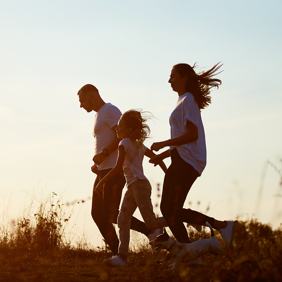 A family is running in a field with a dog