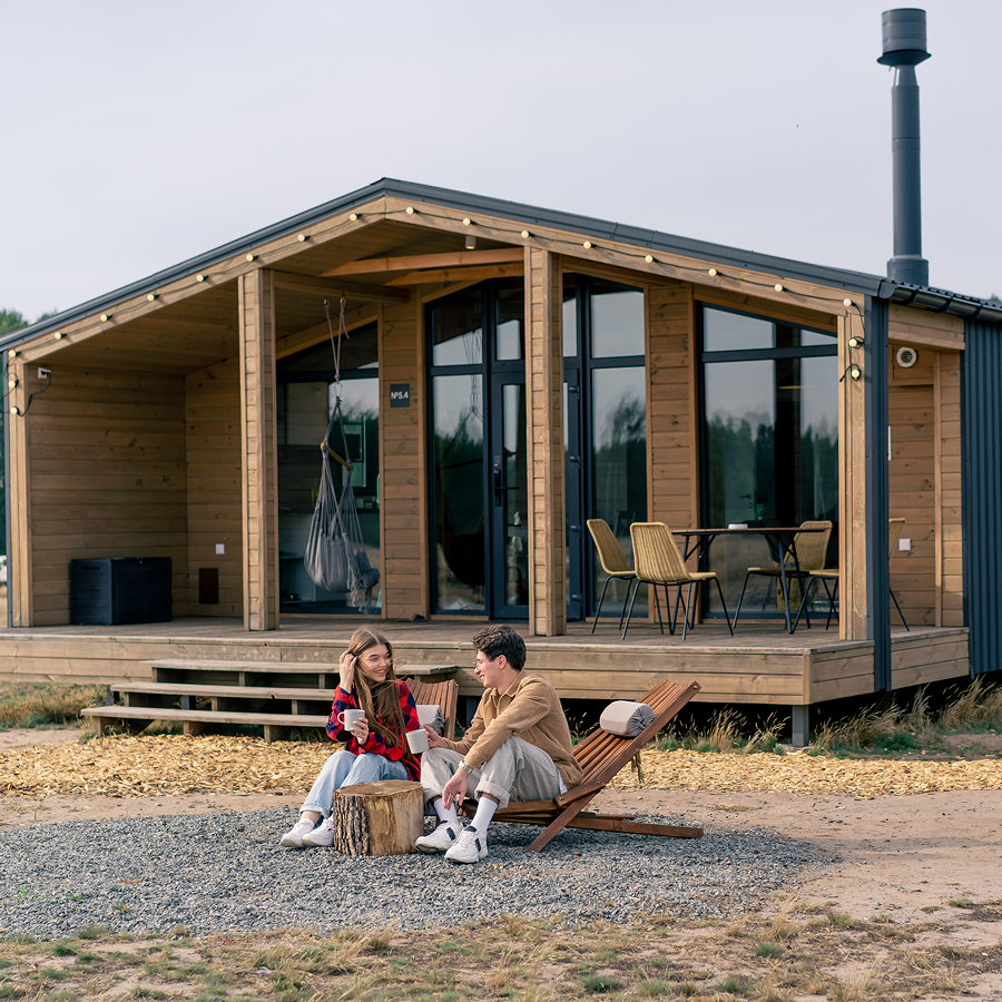 A man and a woman are sitting in front of a wooden house.
