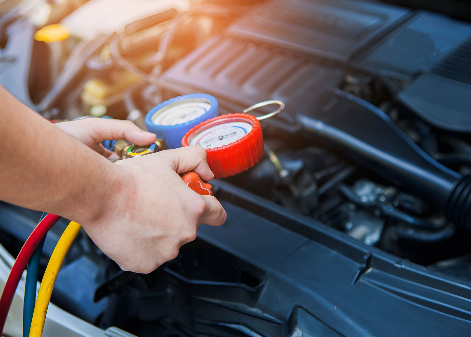 A Person Is Holding A Gauge In Front Of A Car Engine — All Models Service Centre In Port Macquarie, NSW