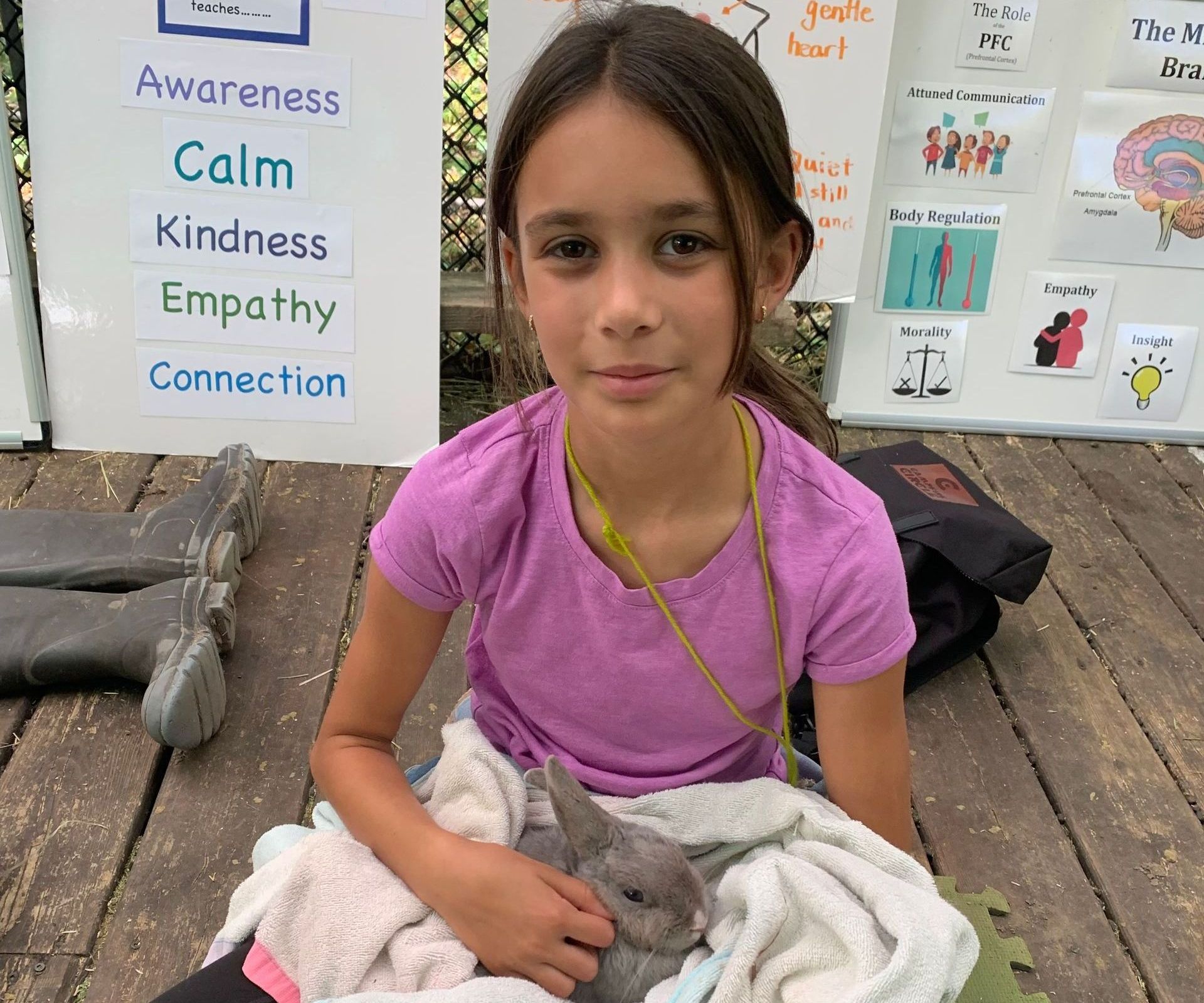 Young girl sitting on wood planks and holding a bunny