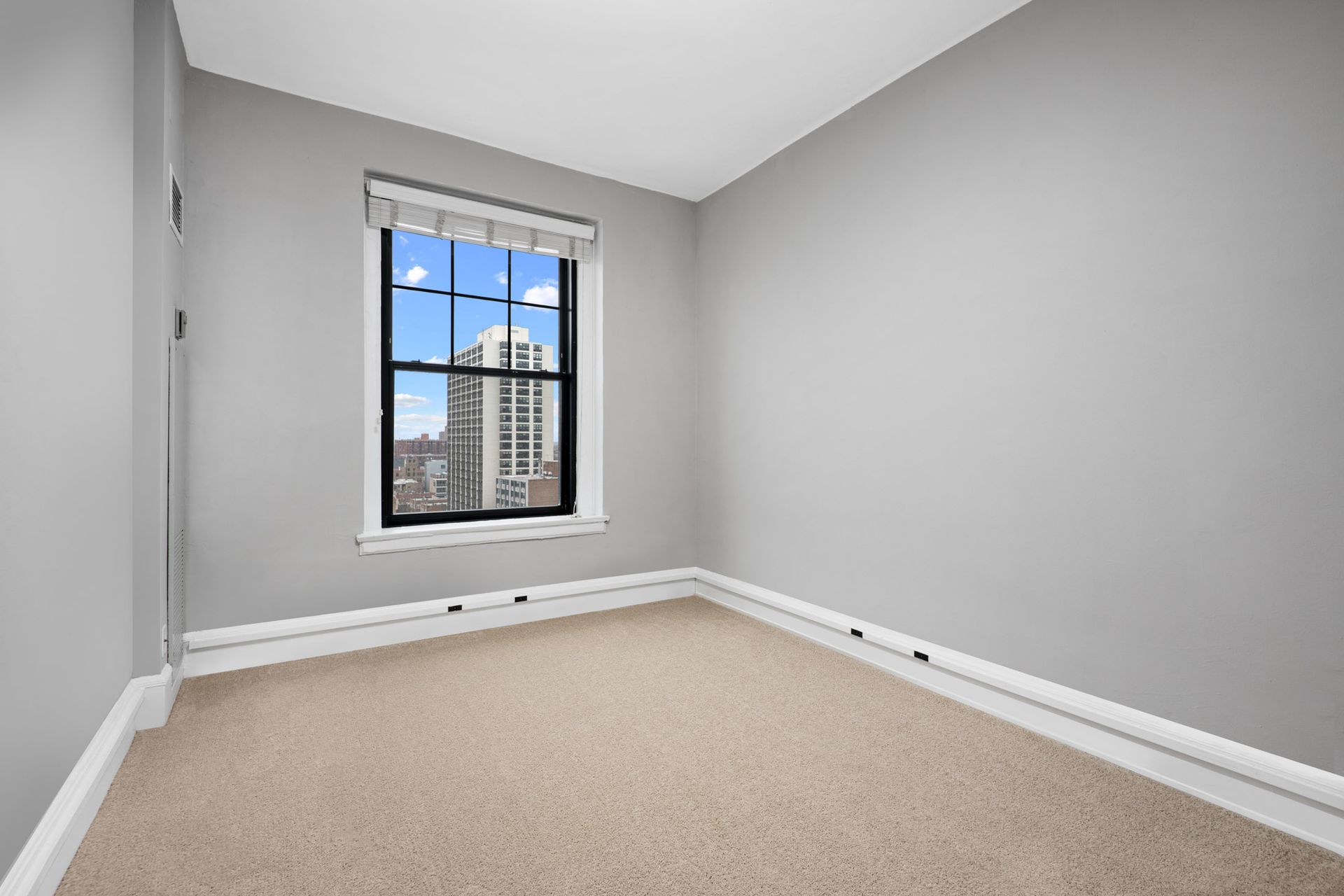 An empty room with a window and a carpeted floor at The Belmont by Reside.
