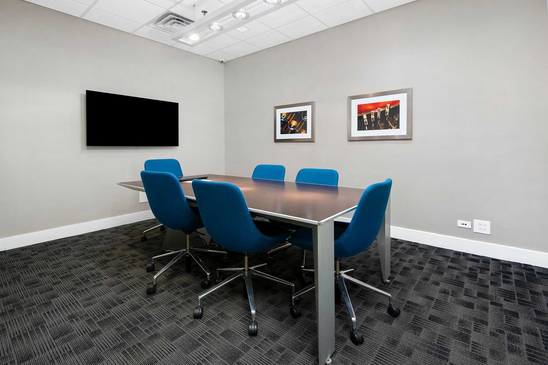 A conference room with a table and chairs and a flat-screen tv at The Belmont by Reside.