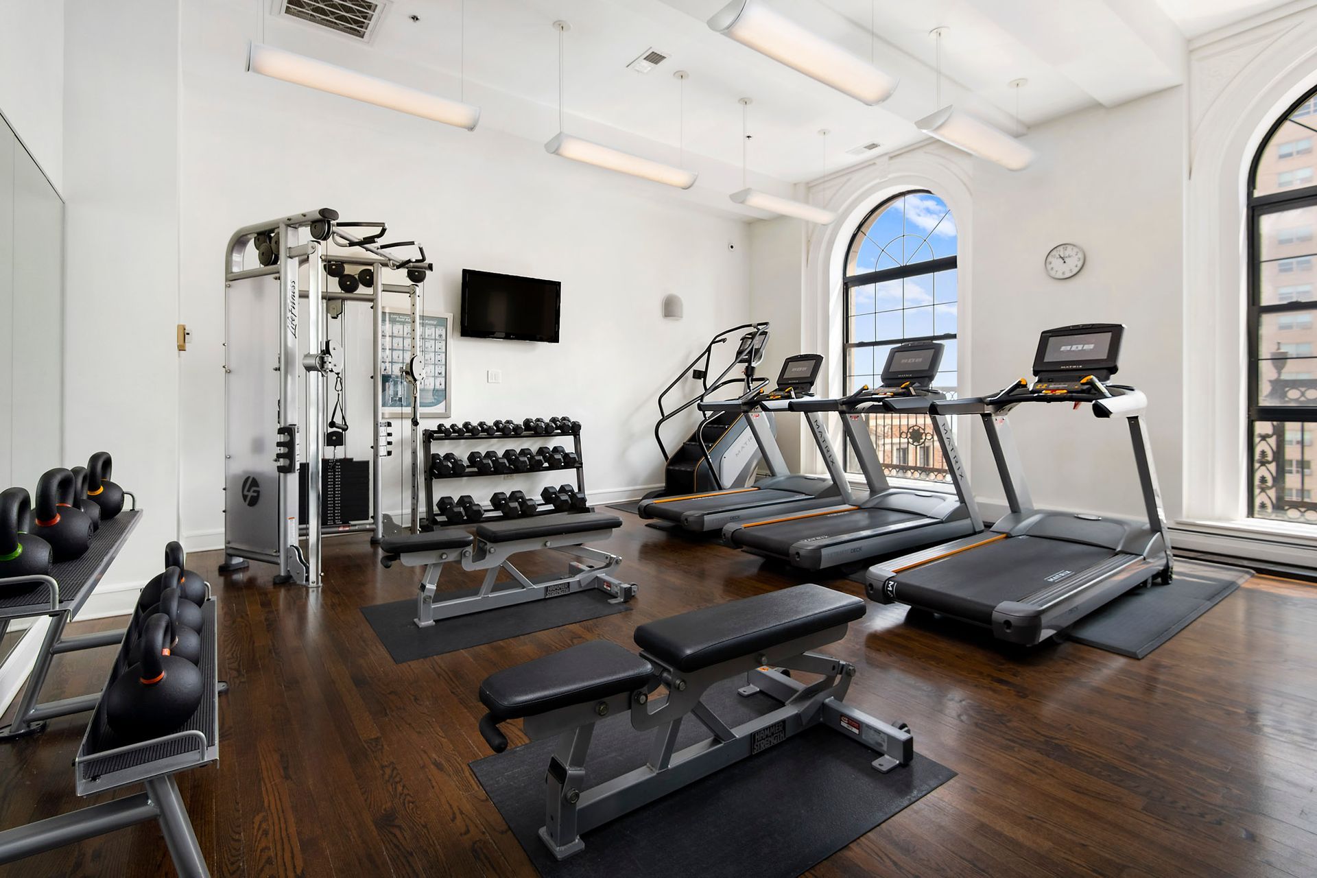 A large gym with treadmills and dumbbells at The Belmont by Reside.