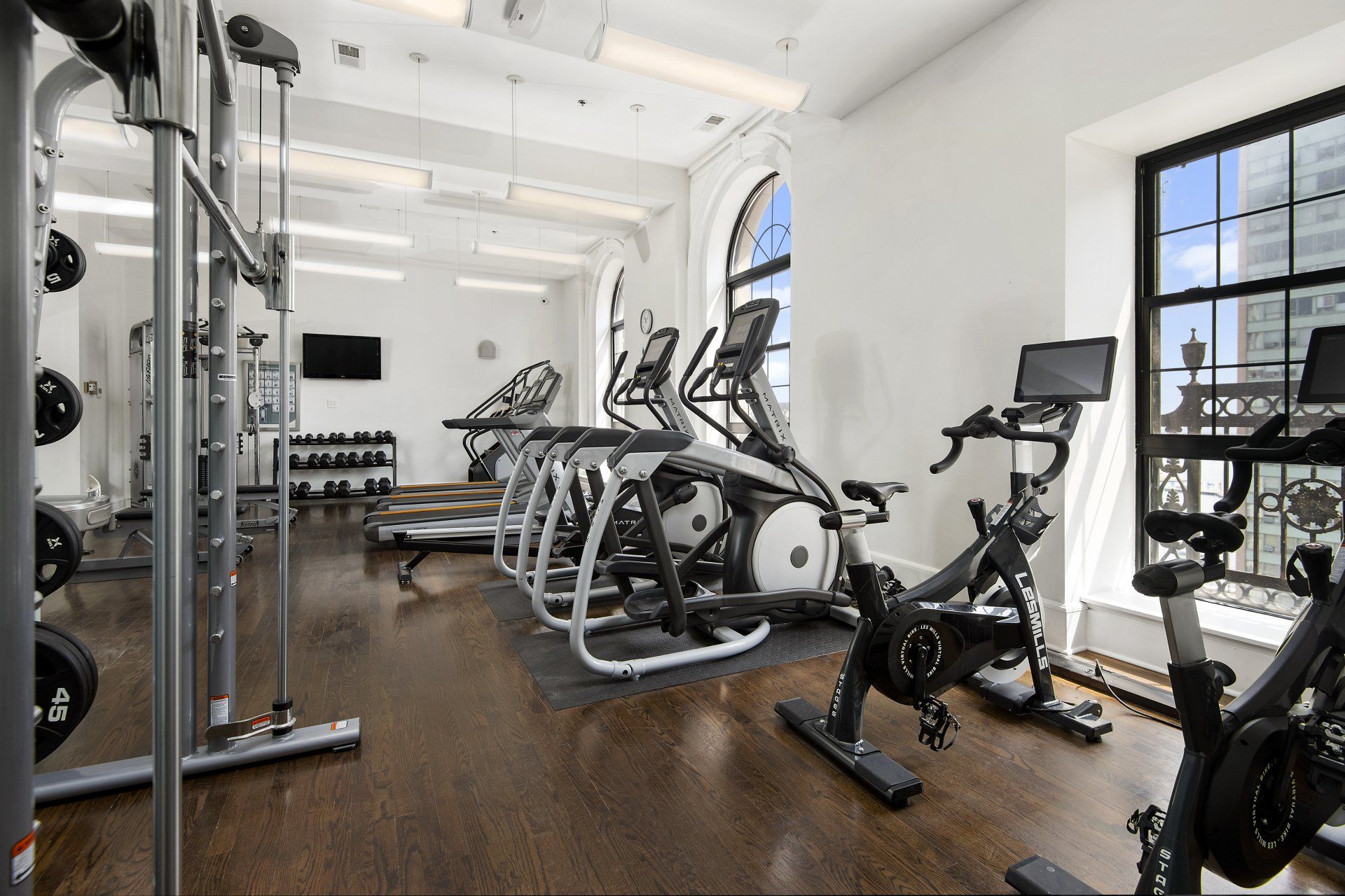 A gym with a lot of exercise equipment and a large window at The Belmont by Reside.