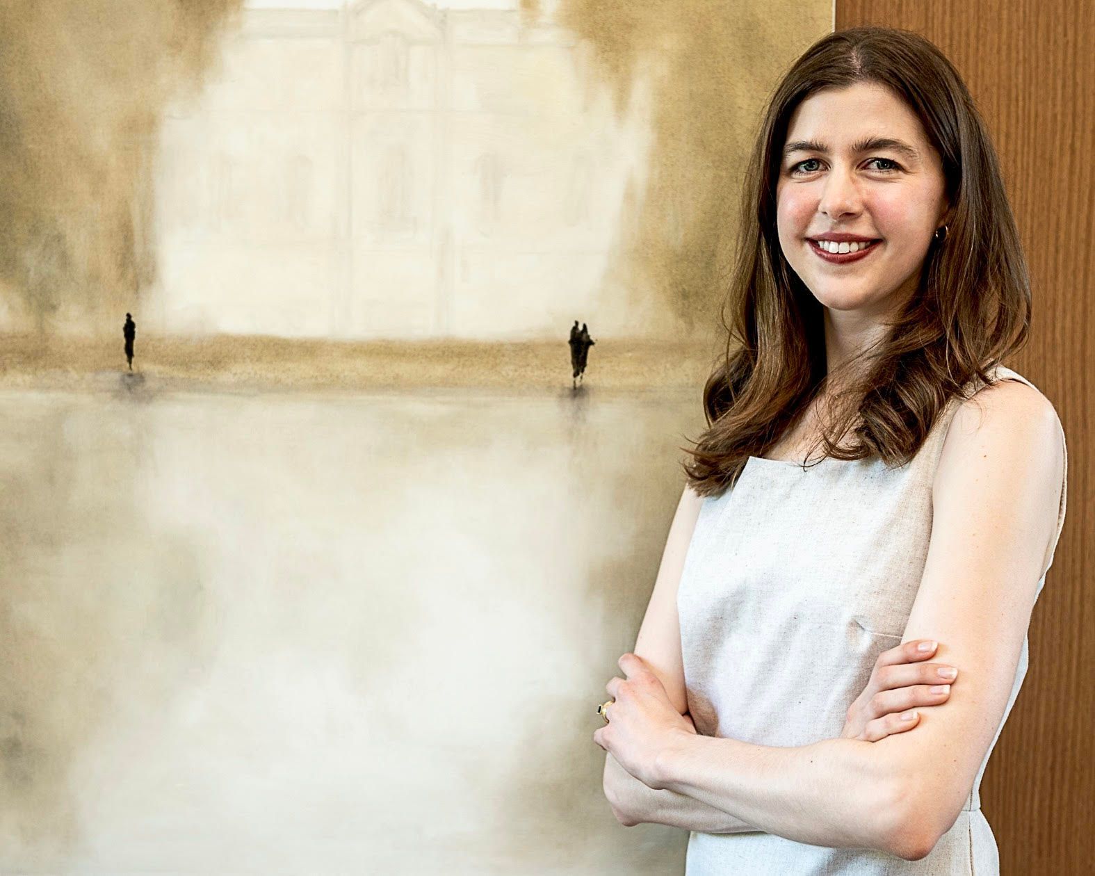 A woman standing in front of a painting with her arms crossed
