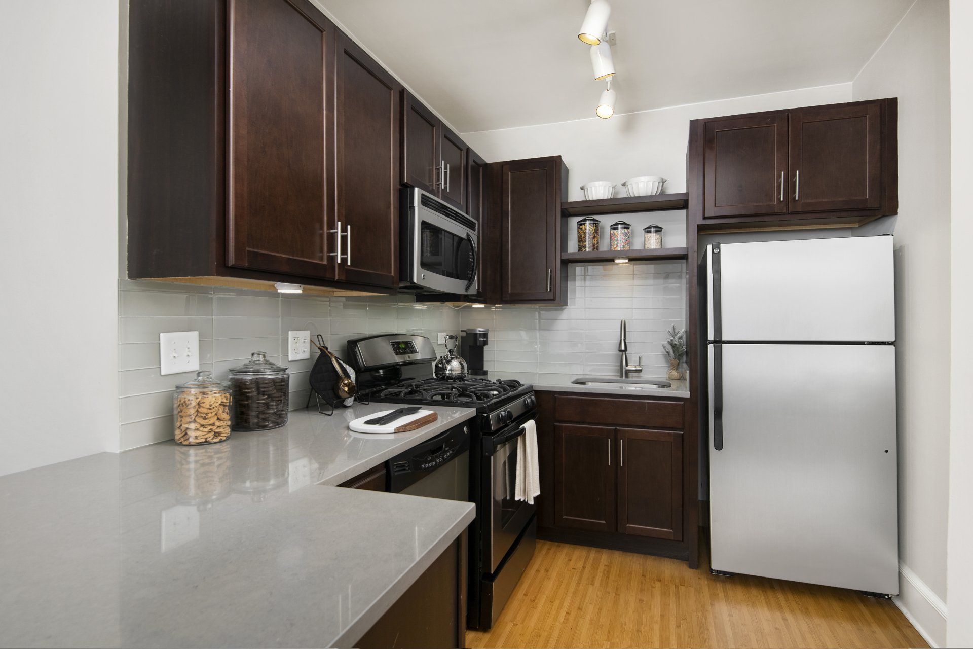A kitchen with stainless steel appliances and wooden cabinets at The Belmont by Reside.