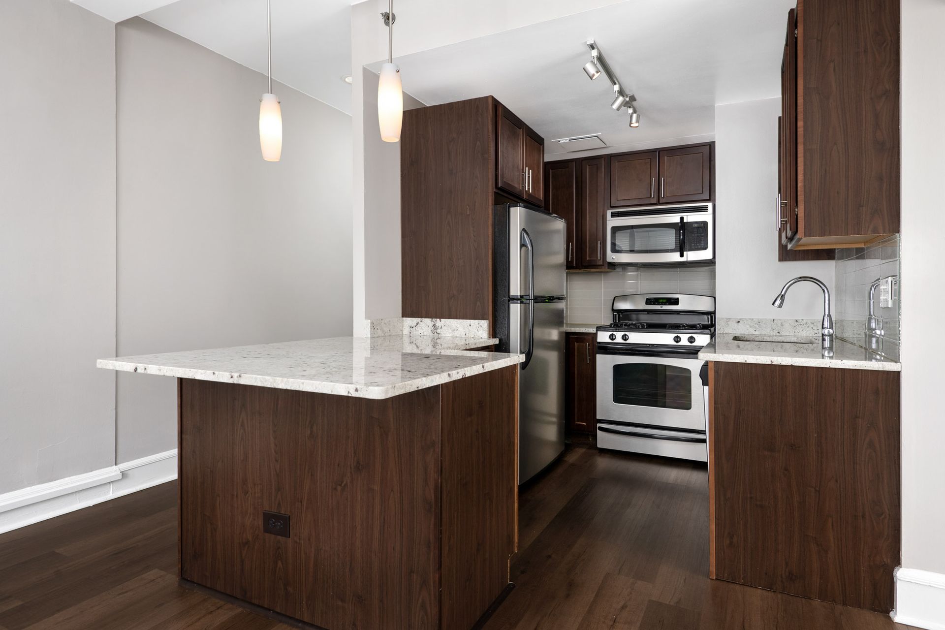 A kitchen with stainless steel appliances and wooden cabinets at The Belmont by Reside.