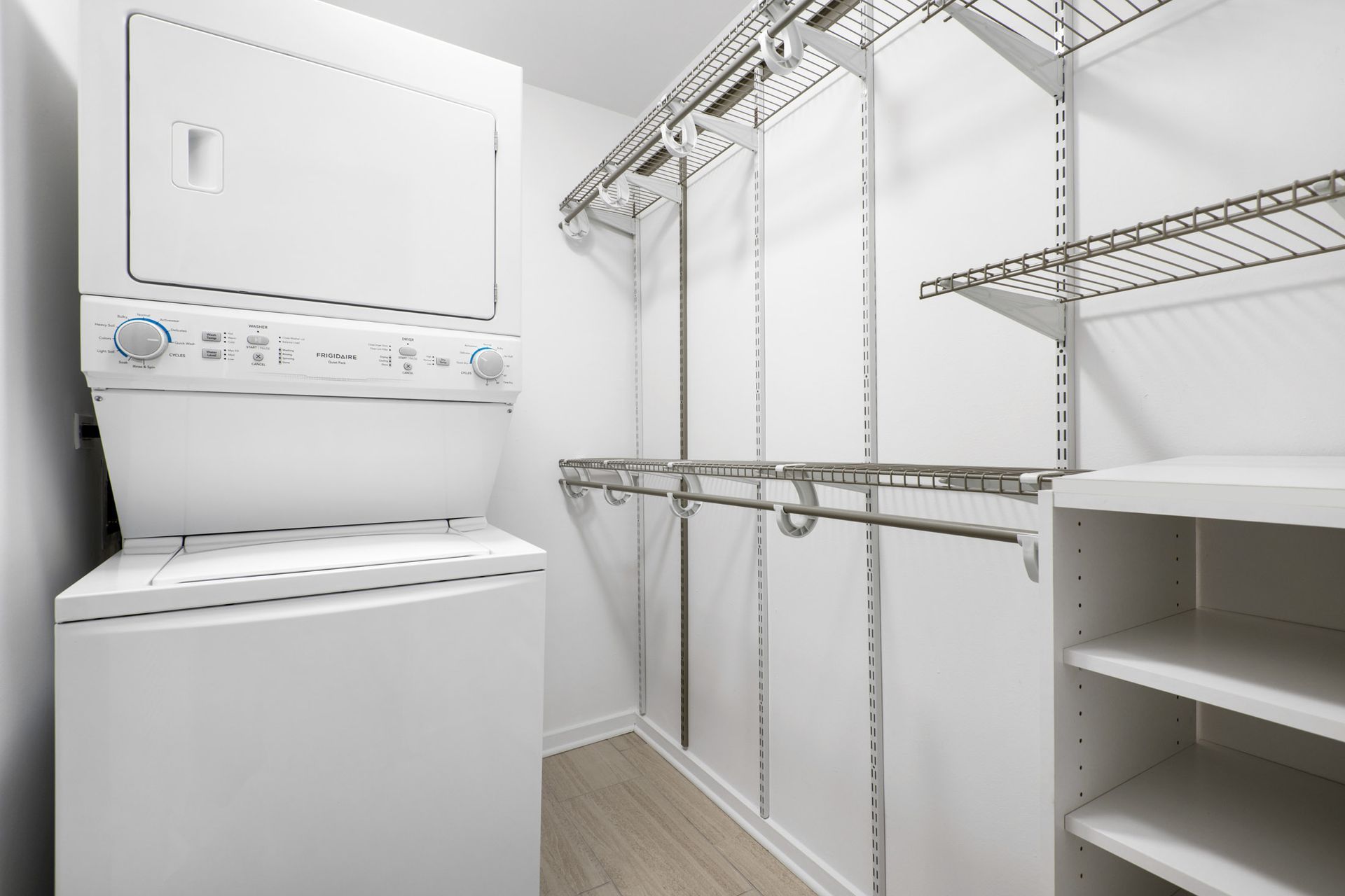 A walk-in closet with a washer and dryer stacked on top of each other at The Belmont by Reside.
