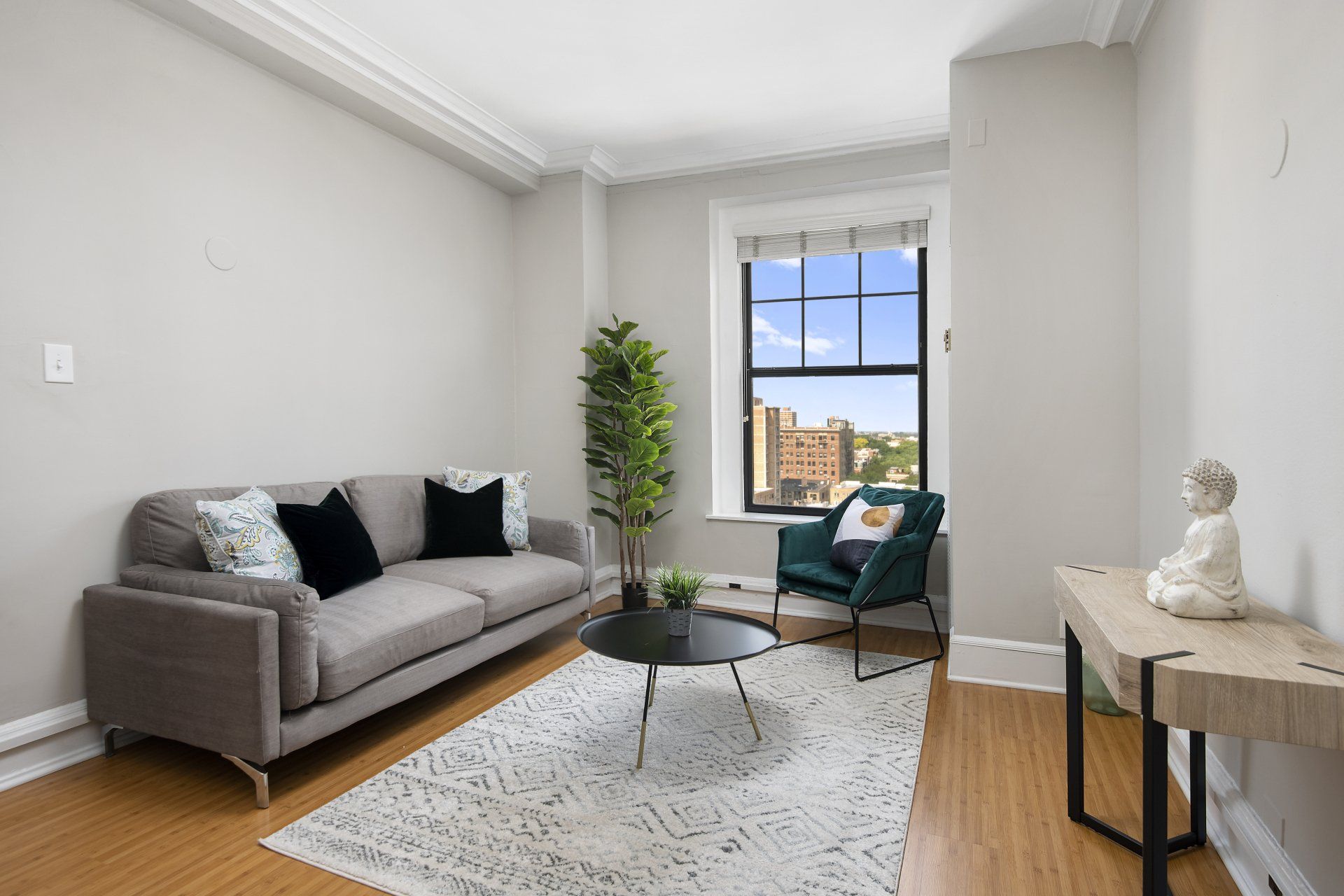 A living room with a couch, chair, table, and window at The Belmont by Reside.
