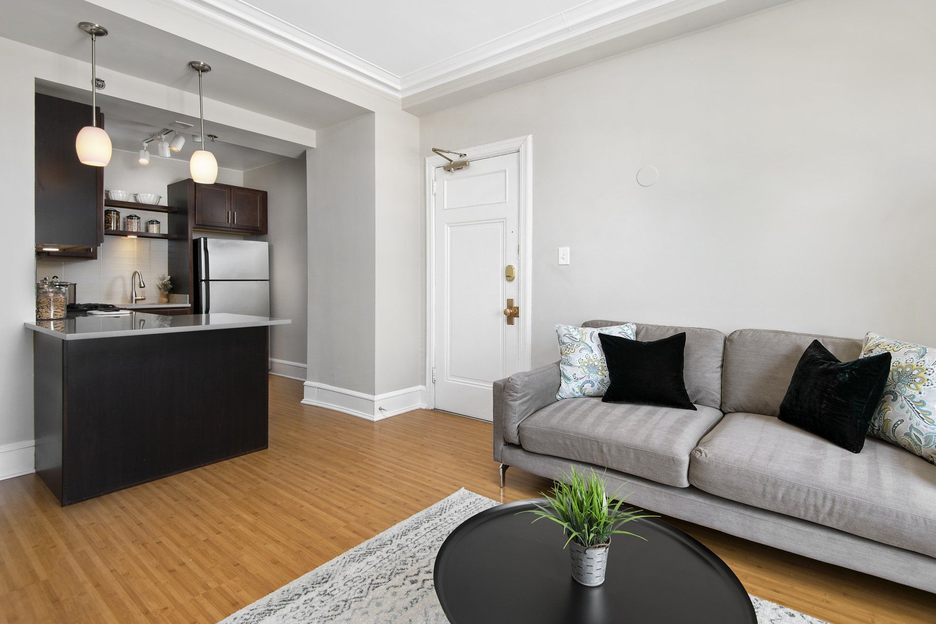 A living room with a couch, table, and kitchen in the background at The Belmont by Reside.