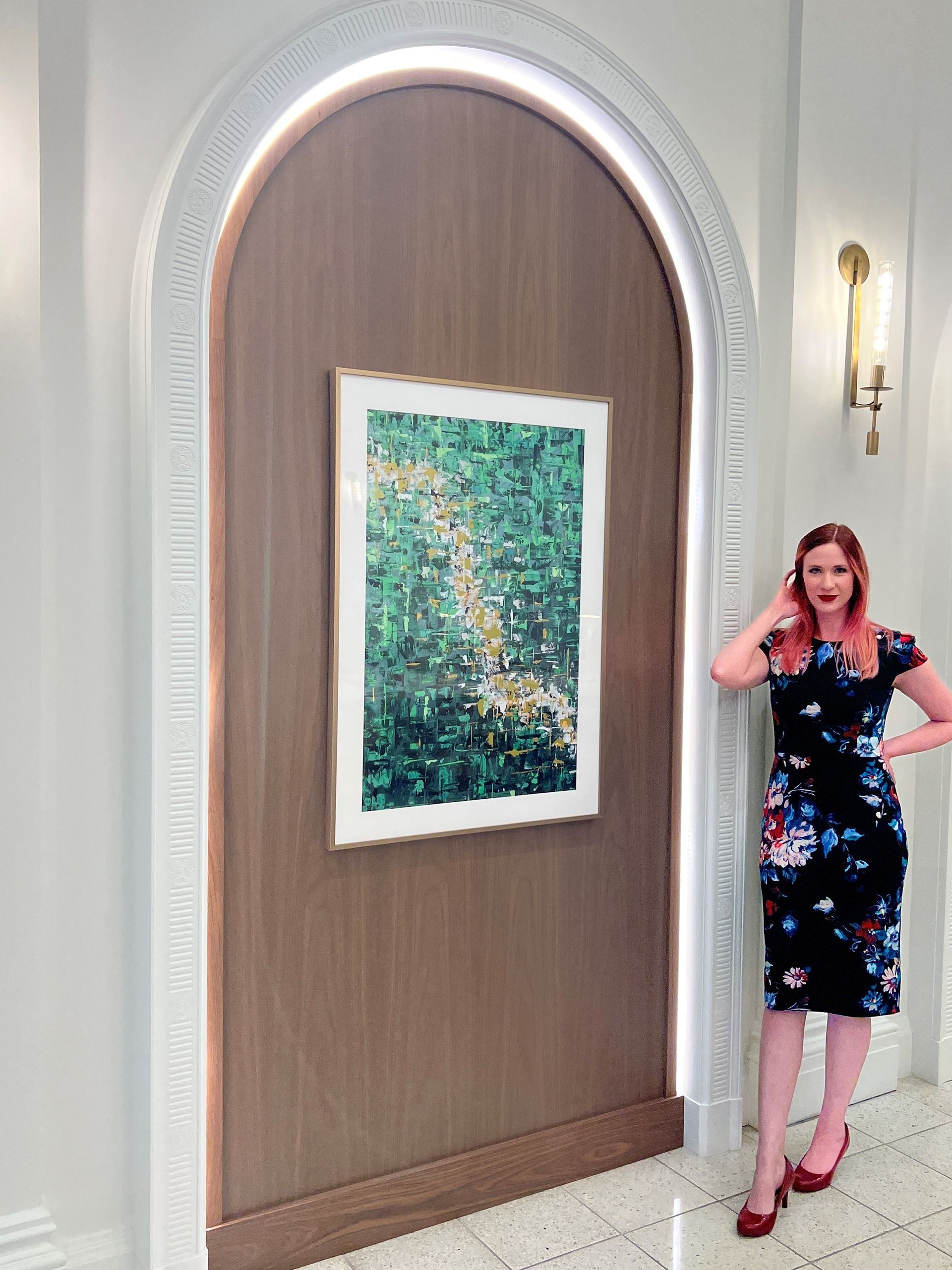 A woman is standing in front of a painting on a wall