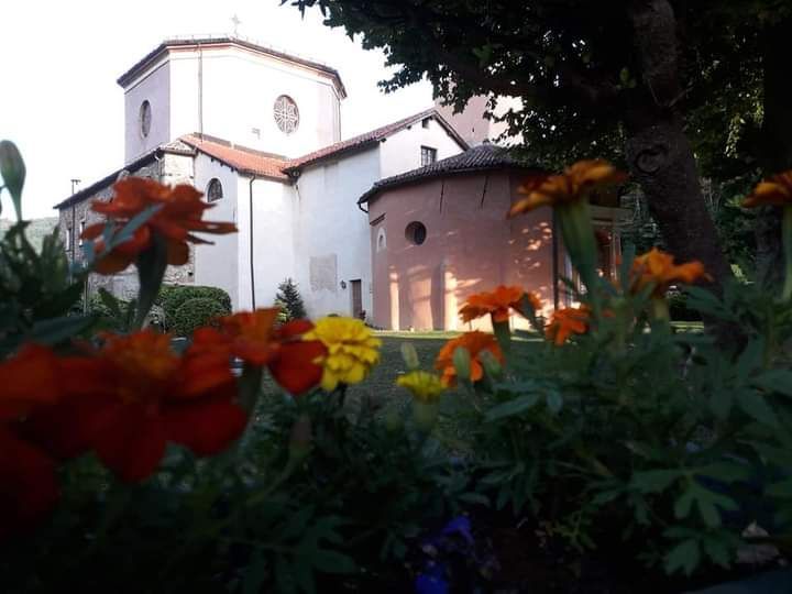 Edificio della chiesa con fiori arancioni e gialli in primo piano.