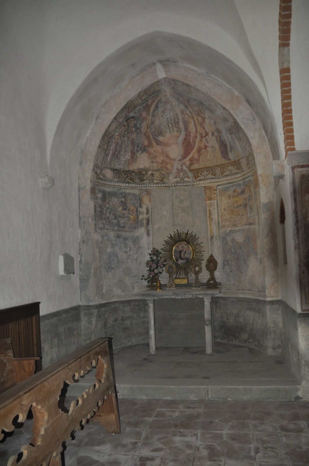 Cappella interna: soffitto a volta, dipinti murali sbiaditi, altare con oggetti religiosi.