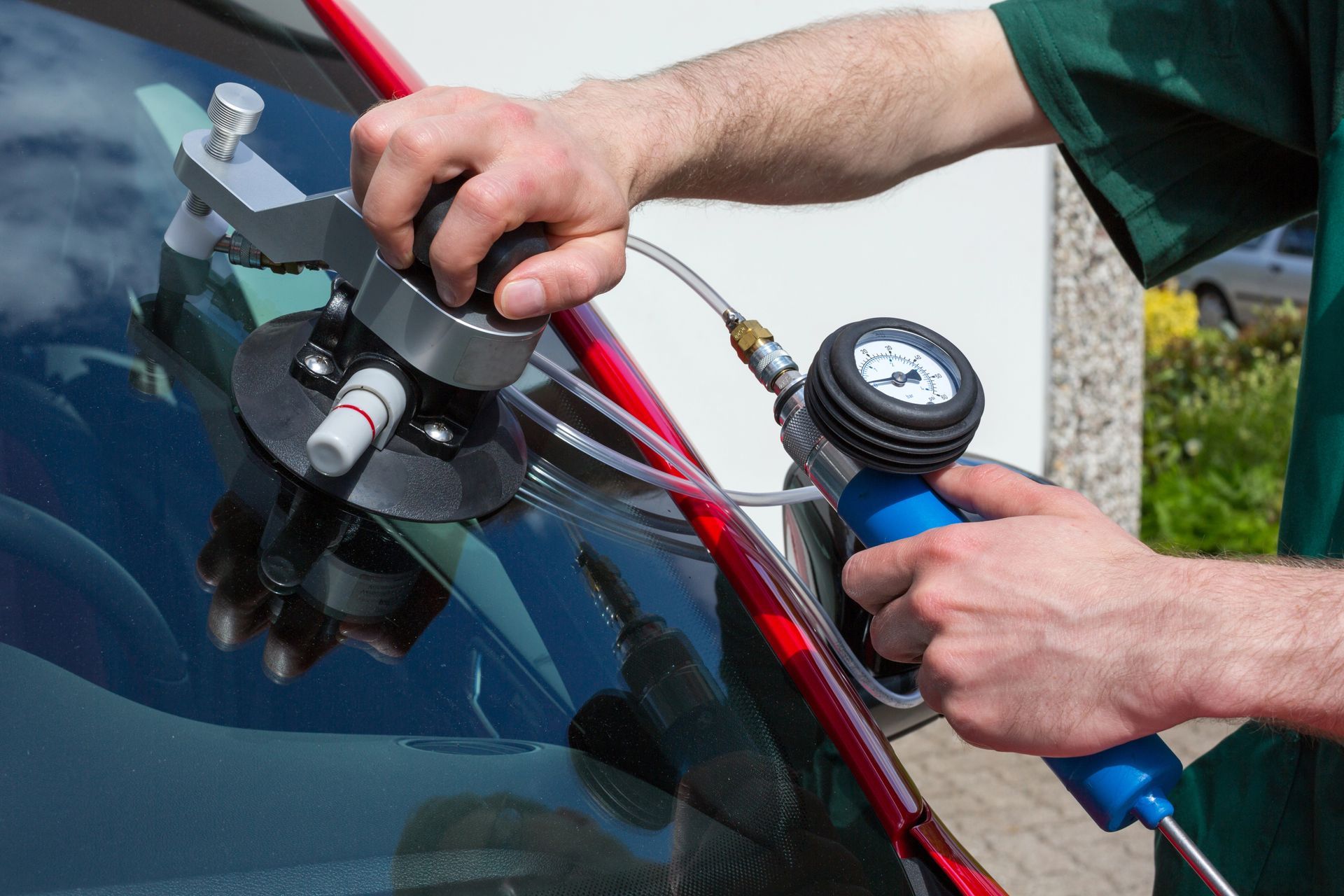 A man is repairing a windshield on a red car.